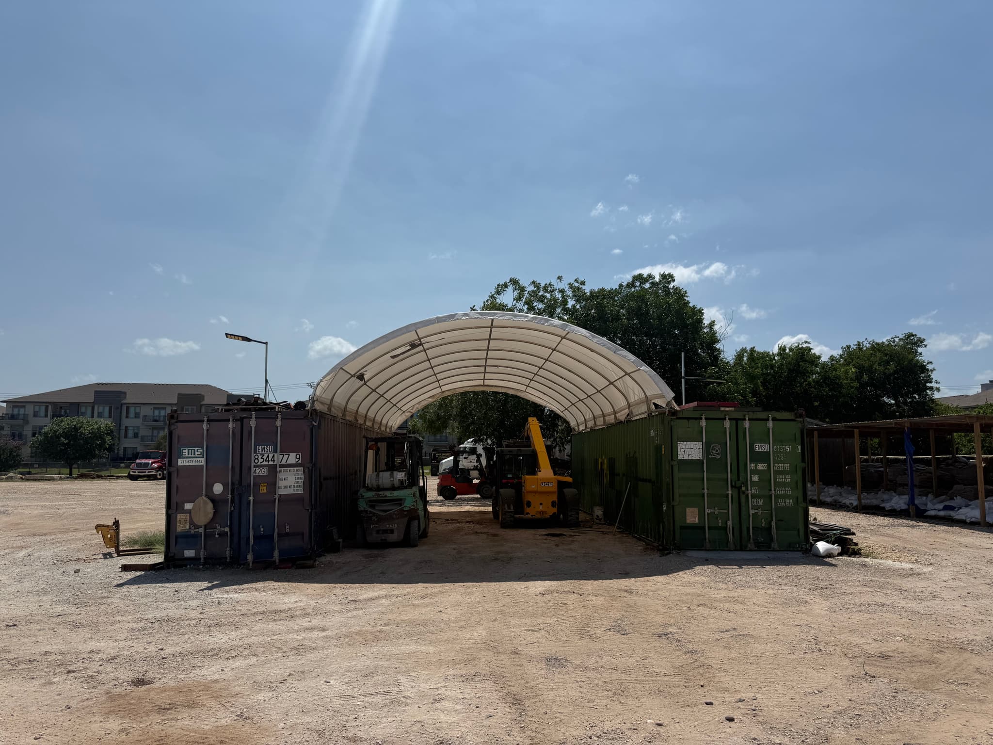 Forklift and loader parked in the equipment yard under a covered storage canopy