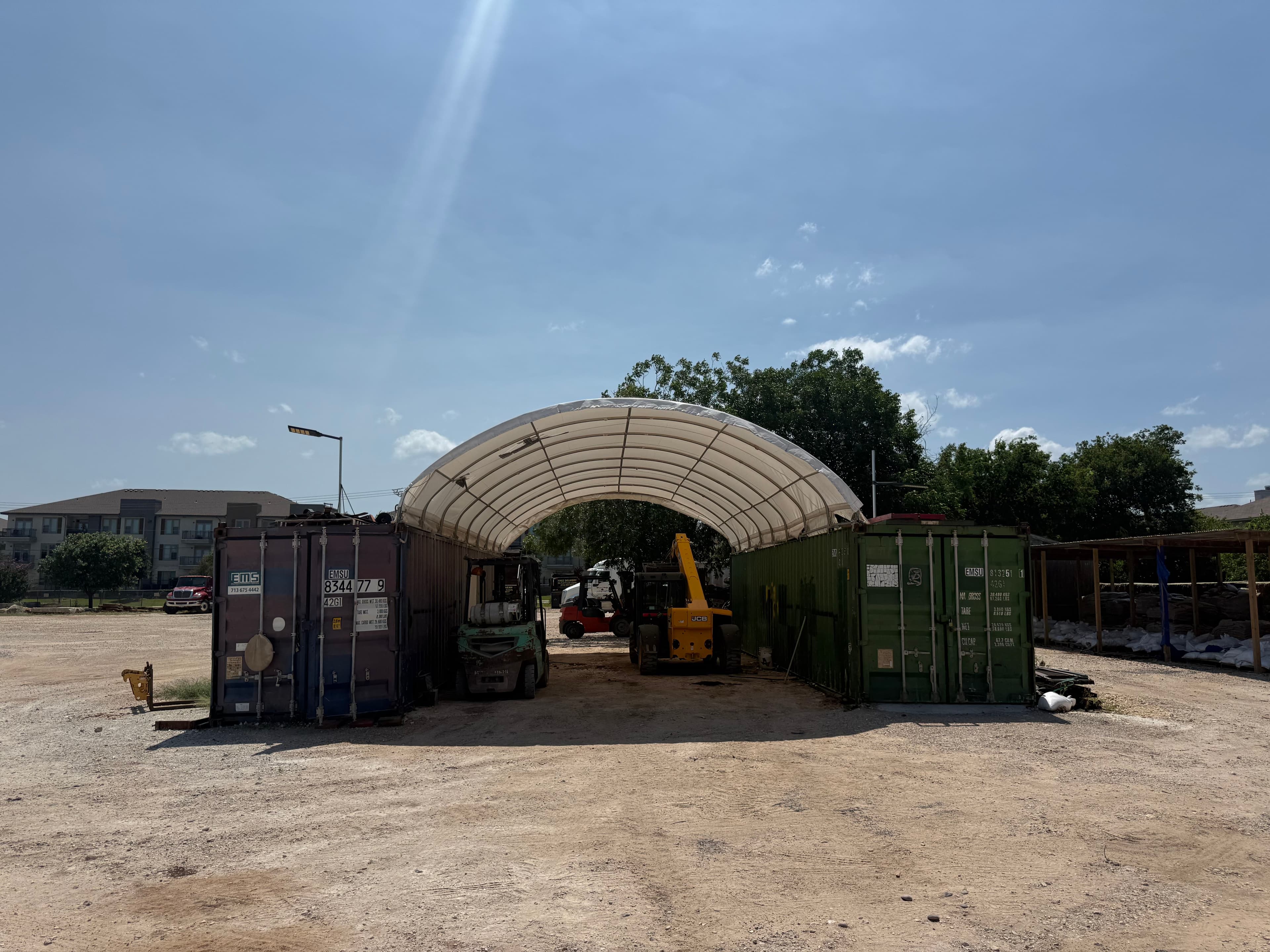 Forklift and loader parked in the equipment yard under a covered storage canopy